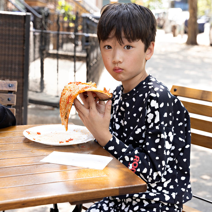 Boy wearing a Rooie and Friends Dalmatian sweatshirt while eating pizza