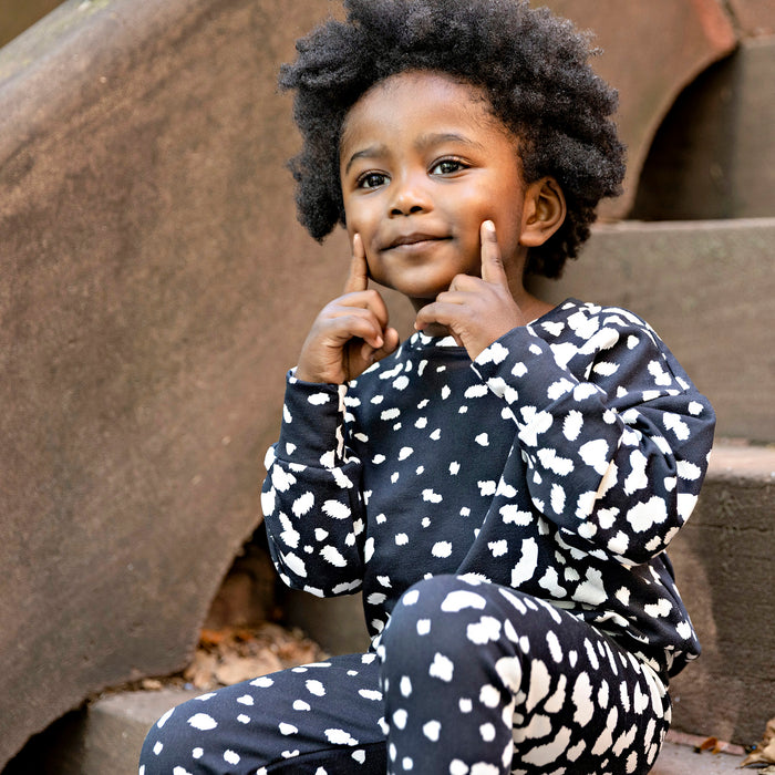 Toddler boy wearing a Rooie and Friends Dalmatian sweatshirt set on brownstone steps