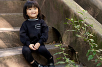 Girl wearing a Rooie and Friends black sweatshirt with silver trim at a basketball court