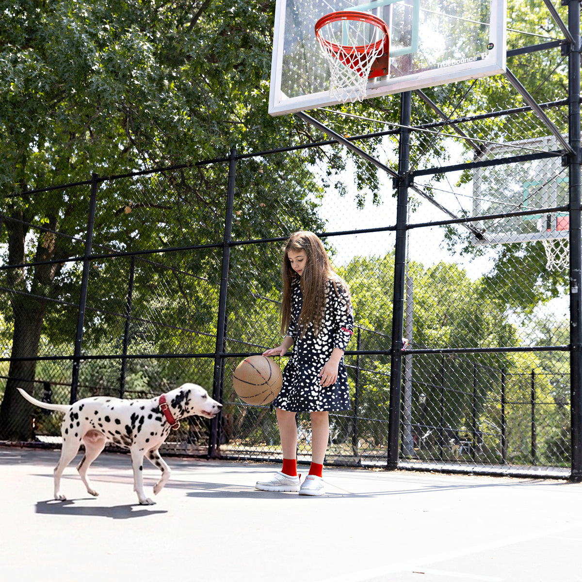 Girl wearing a Rooie and Friends Dalmatian ruffle dress at a basketball court