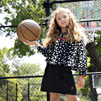Girl wearing Rooie and Friends Dalmatian ruffle sweatshirt at a basketball court