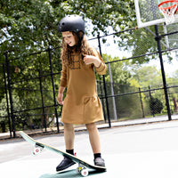 Girl wearing a Rooie and Friends caramel ruffle dress while skateboarding