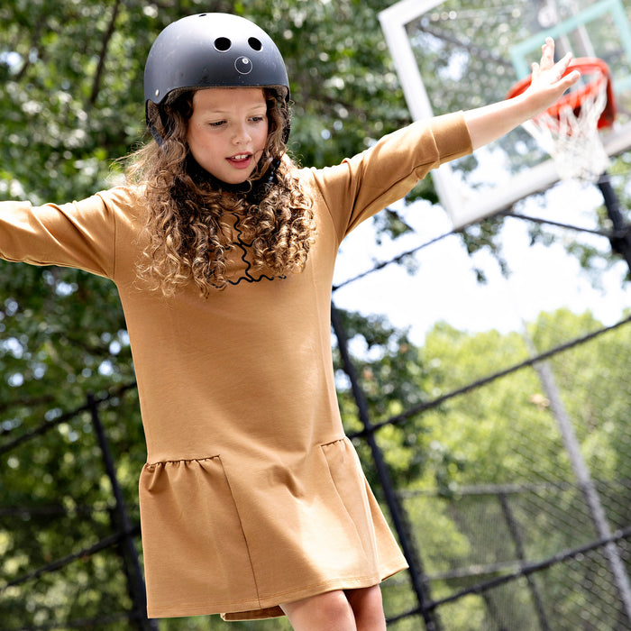 Girl wearing a Rooie and Friends caramel ruffle dress while skateboarding
